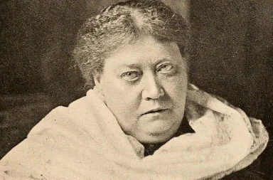 Historical portrait of Helena Blavatsky looking forward with a white shawl around her shoulders, illustrating her masterpiece.