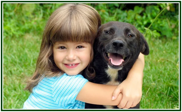 A young girl smiling and hugging a happy dark dog on green grass, illustrating the bond of theosophy and trust.
