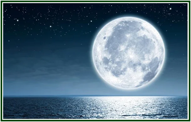 Fotografia da lua cheia em plano aproximado com luz prateada a refletir no mar e horizonte noturno.